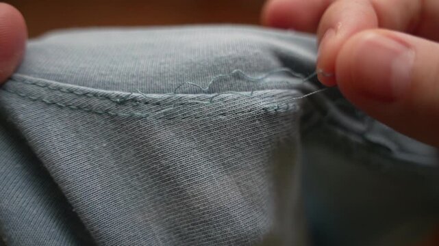 Close-Up of T-Shirt Falling Apart at Seams &ndash; Stitches Unraveling and Fabric Damage