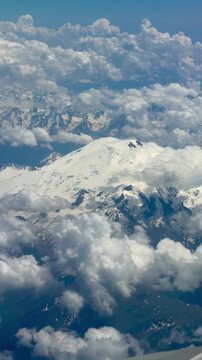  Mount Elbrus from airplane window: snow‑covered dome amid clouds &mdash; vertical