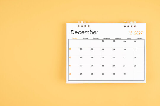December 2027 desk calendar on yellow color background, position with copy space.