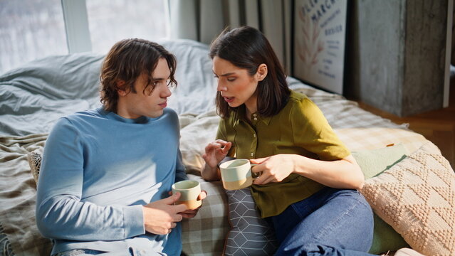 Chatting duet drinking tea bedroom interior closeup. Love pair discussing news