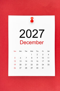 December 2027 calendar page with push pin on red color background.