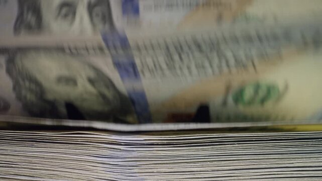 Front view of a money counting machine processing 100 dollar bills. Modern financial technology for banks, exchange offices, retail and secure cash handling.