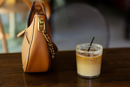 Iced coffee with a purse on a cafe table
