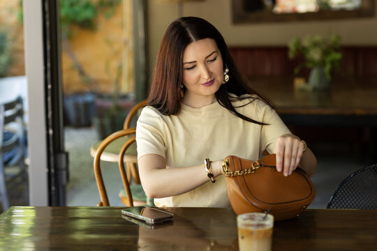 Woman enjoying coffee in a cafe while checking handbag