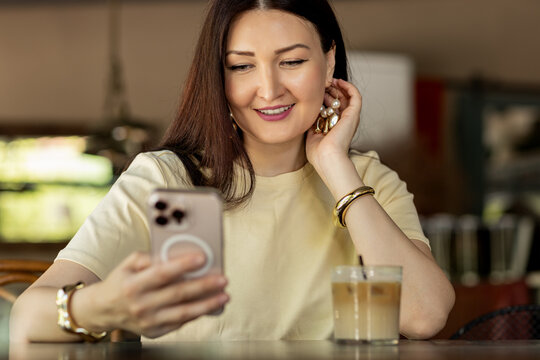 Woman enjoying coffee while using her phone in cafe