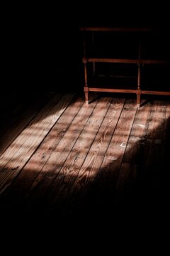 Empty wooden bench in warm sunlight on hardwood floor. Minimalist seating in natural golden light for serene indoor setting.