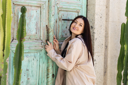 Smiling woman by rustic turquoise door with cactus