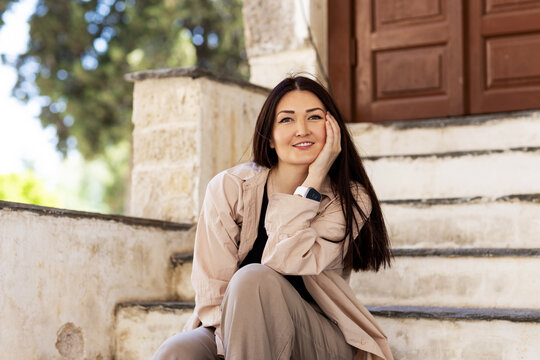 Smiling young woman sitting on stone steps outdoors