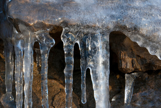 Shimmering icicle curtain on winter rock surface close up