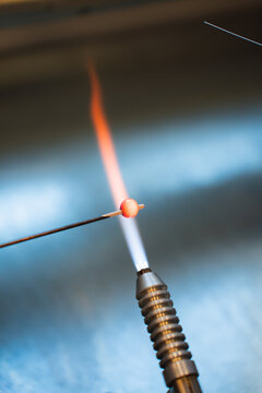 Artisan crafting glass bead over flame in Lofoten workshop