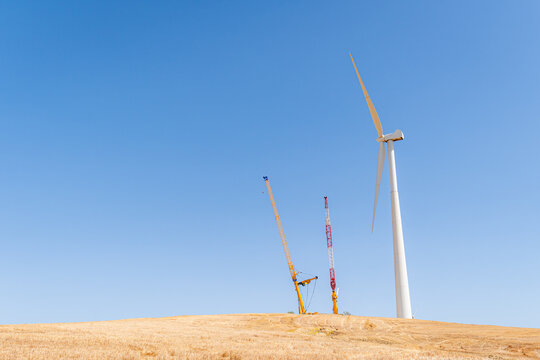 Wind turbine installation with cranes on a hill