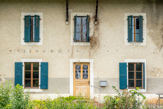 Rustic house facade with blue shutters and wooden door