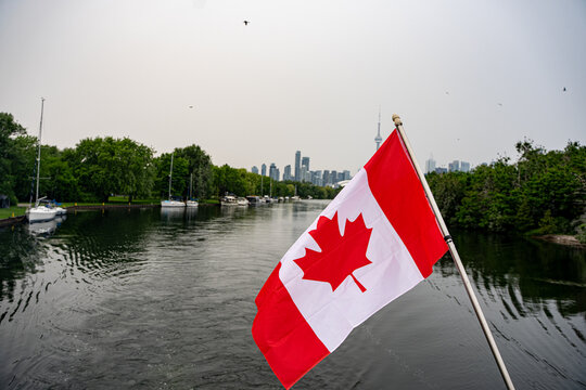Canadian flag with Toronto skyline in background.