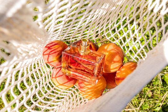 Perfume bottle with peach in a mesh bag in sunlight