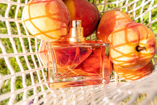 Peach perfume bottle with fresh peaches in summer light