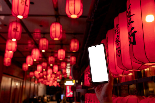 Smartphone mockup held under red Chinese lanterns at night