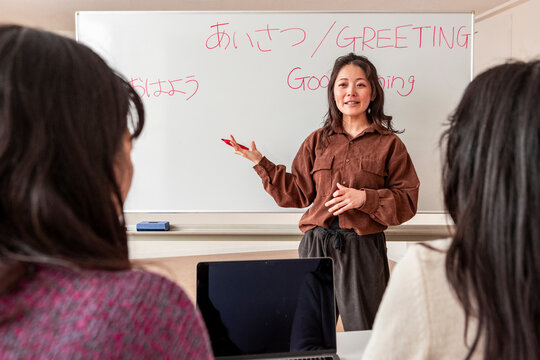 Adult Japanese lesson on greetings with teacher at whiteboard