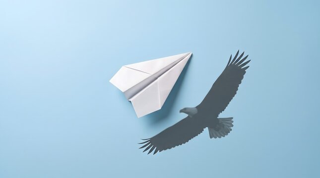 A conceptual image of a simple white paper airplane flying, casting the surprising shadow of a powerful eagle against a light blue background