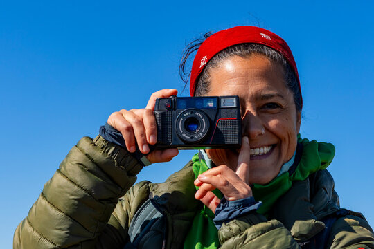Smiling traveler taking a photo with compact camera outdoors
