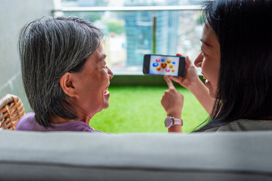 Senior Asian mum and daughter learning smartphone app together