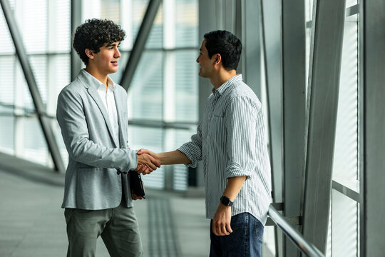 Business partners shaking hands in modern office corridor