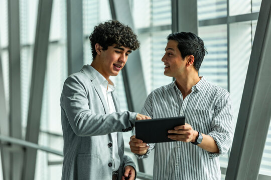 Two coworkers discussing data on tablet in modern office