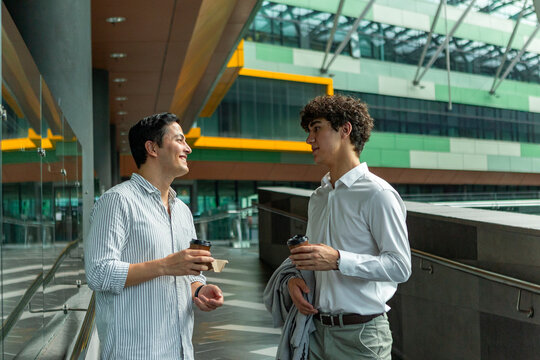 Business colleagues chatting over coffee in modern atrium