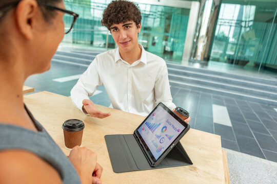 Business meeting with tablet analytics in modern office lobby