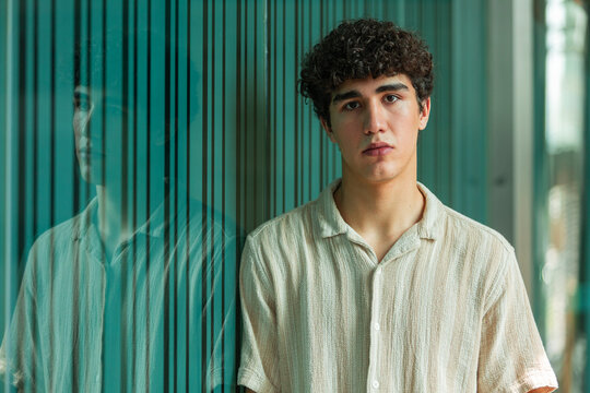 Young man portrait by glass wall with reflection indoors