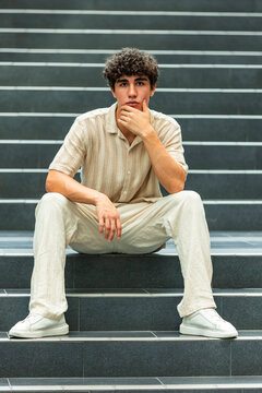 Thoughtful young man sitting on urban stair