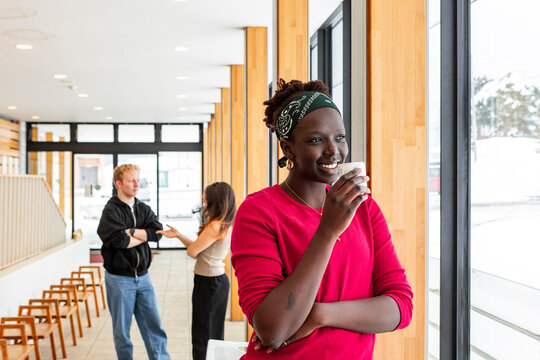 Student coffee break in modern campus hallway by window
