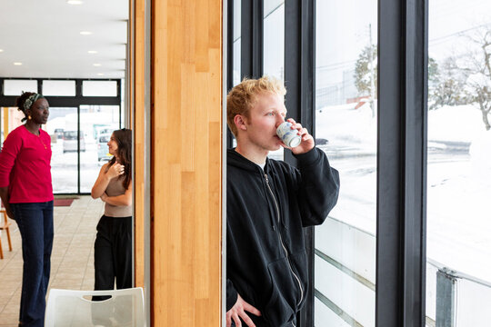 Student sipping coffee by window during campus break time
