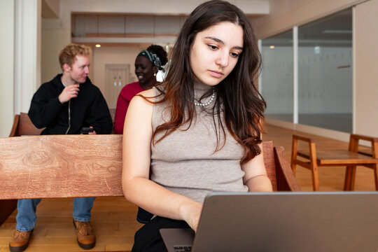 Female student studying on laptop in campus lounge indoors