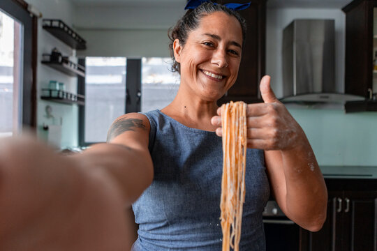 Smiling woman holding handmade pasta dough in home kitchen