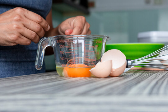 Cracking an egg into measuring cup for home baking prep