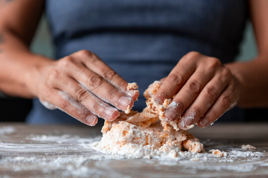 Woman preparing handmade pasta dough on floured table