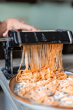 Handmade pasta dough being cut through a pasta machine