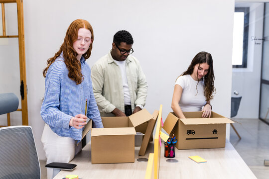 Office team packing cardboard boxes for relocation and setup