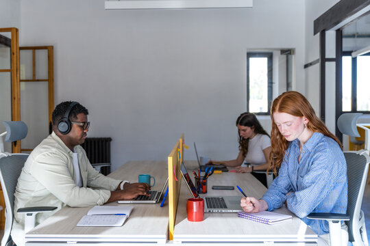 Coworkers working quietly at shared desk in bright office