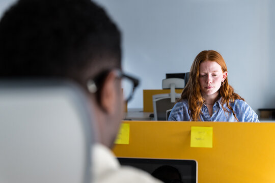 Focused woman working at office desk with notes and computer