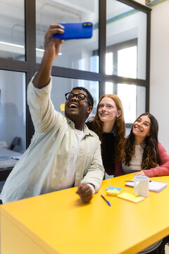 Diverse coworkers taking a selfie in modern office