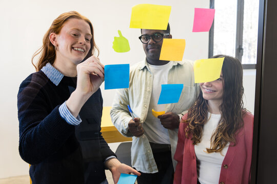 Team brainstorming with sticky notes on office glass wall