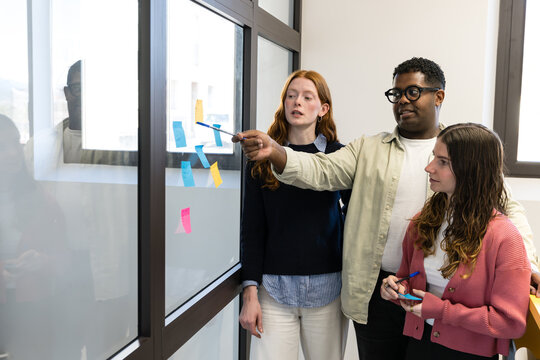 Team planning session using sticky notes on office glass