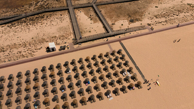 Empty beach with straw umbrellas and sun loungers coastal area during daytime