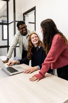 Diverse coworkers collaborating on laptop in modern office