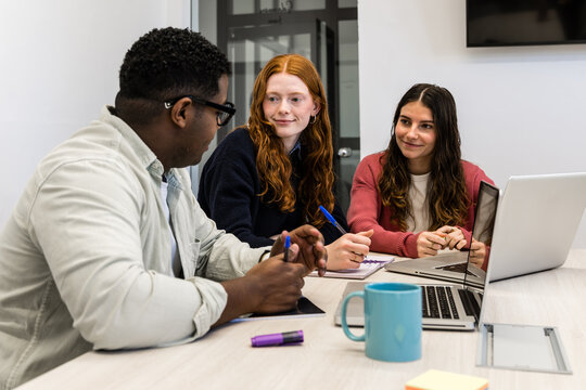 Diverse team meeting and planning around laptop in office