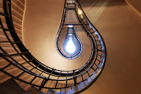 Staircase in Prague creates the illusion of a glowing light bulb, with curved railings, symmetry and geometric lines forming a striking abstract architectural design.