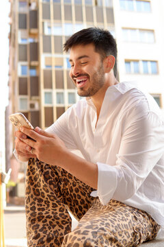 Fashionable Hispanic man using smartphone in city apartment