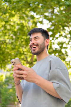 Stylish urban Hispanic man using smartphone in park