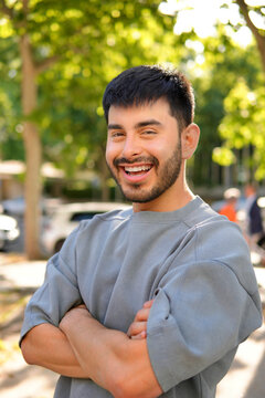 Stylish Hispanic man smiling outdoors in city park portrait